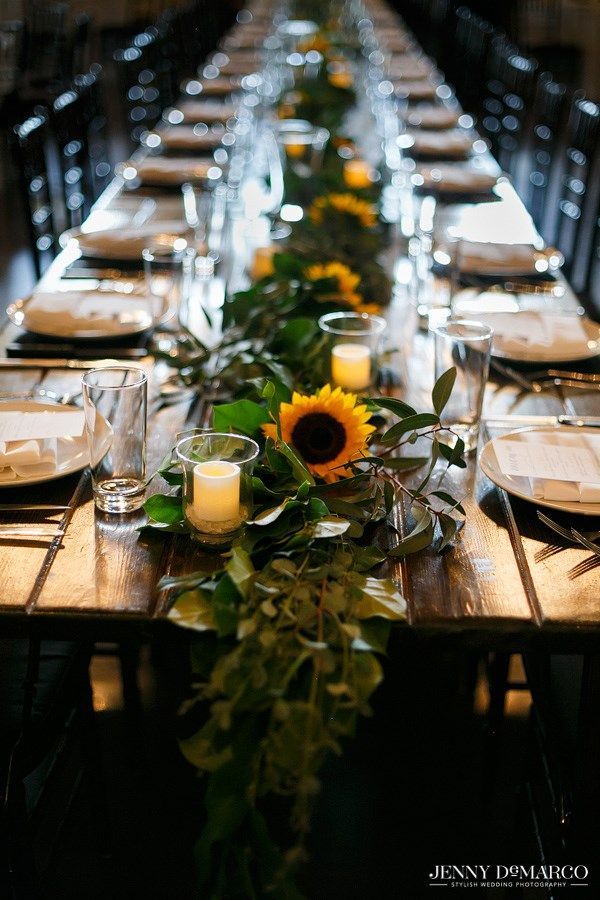 the long table is set with sunflowers and greenery for an elegant dinner