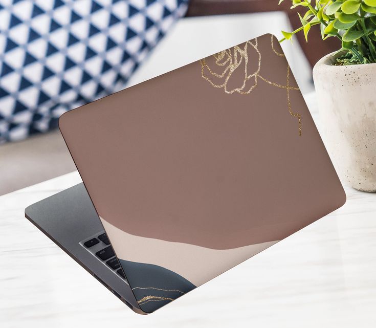 an open laptop computer sitting on top of a table next to a potted plant