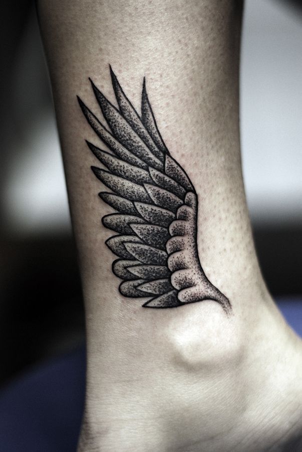 a black and white photo of a foot with a wing tattoo on it