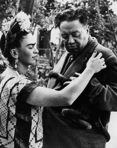 a man and woman standing next to each other in front of trees with flowers on their head