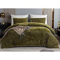 a bed covered in a green comforter and pillows