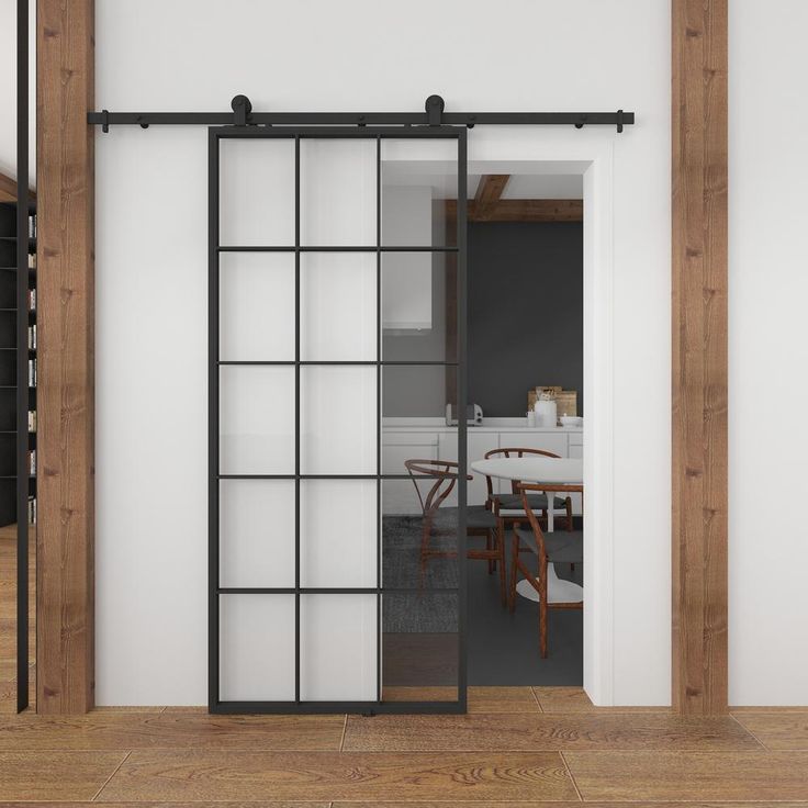 an open door leading to a kitchen and dining area with wooden floors, white walls and wood trimmings