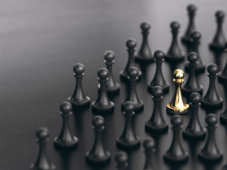 black and gold chess pieces are arranged in a row on a table with one king standing out from the crowd