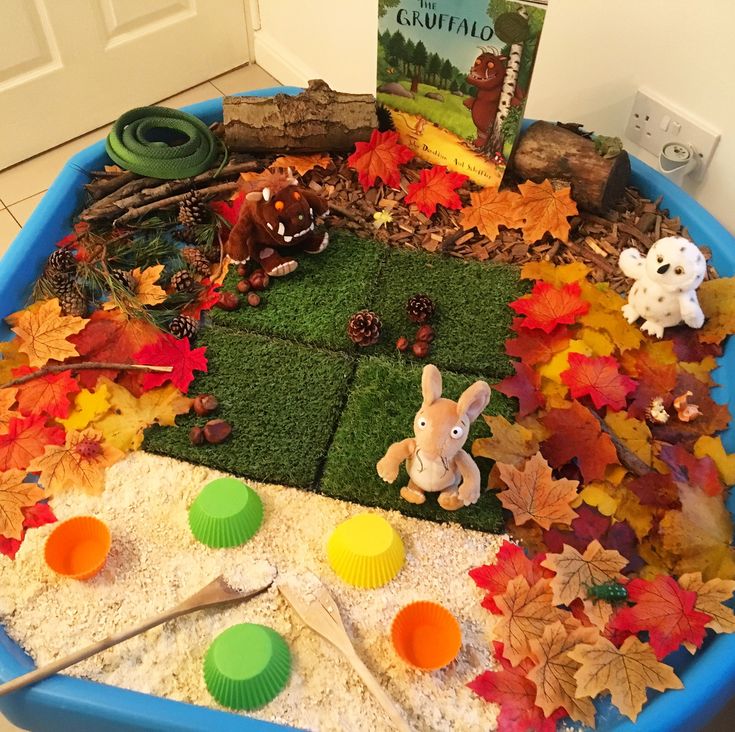 a blue tray filled with lots of leaves and toys