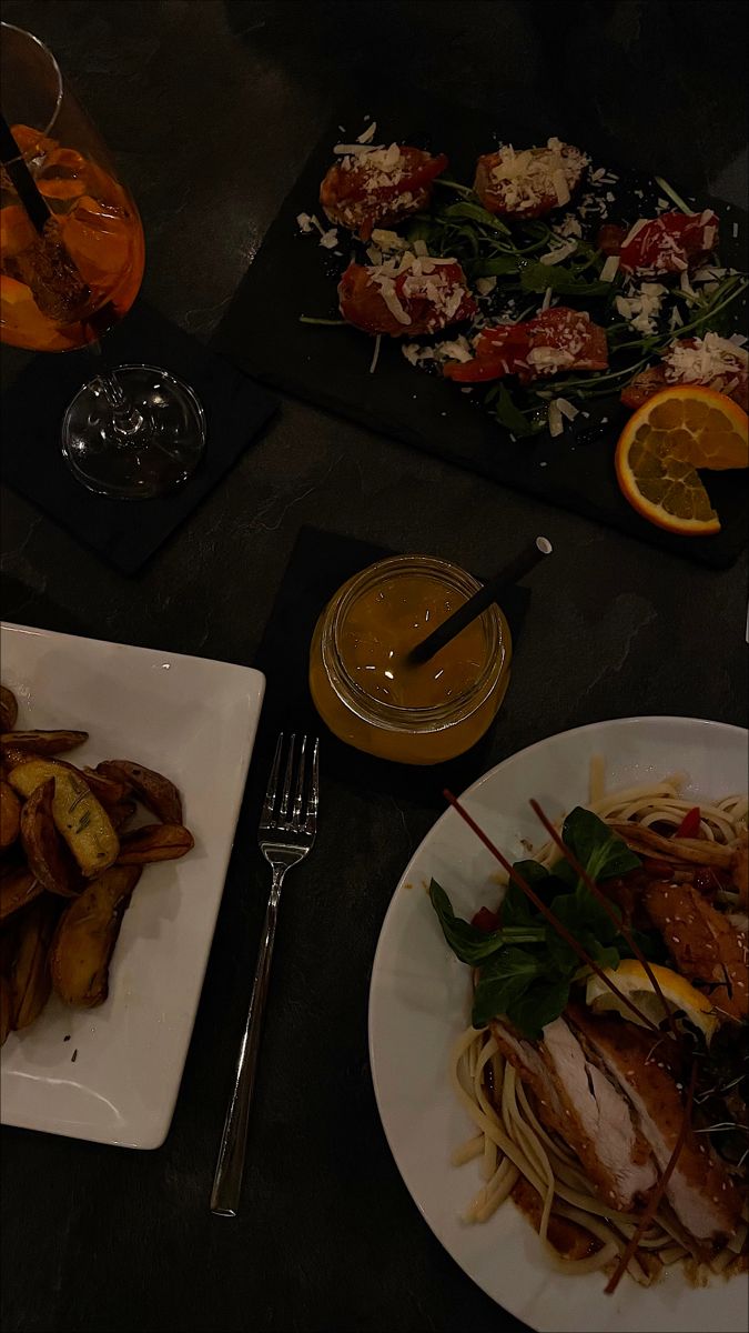 two plates of food on a table with utensils and drinks next to them