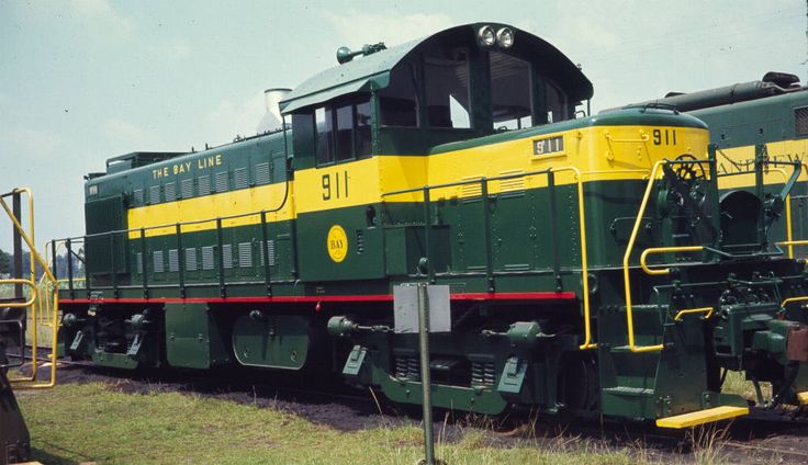 a green and yellow train engine sitting on the tracks