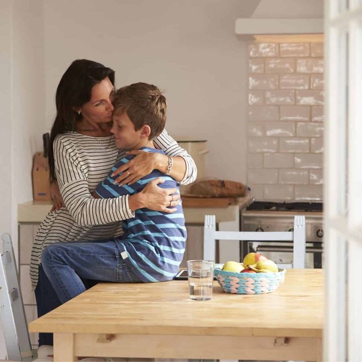 a woman hugging a young boy on the kitchen table