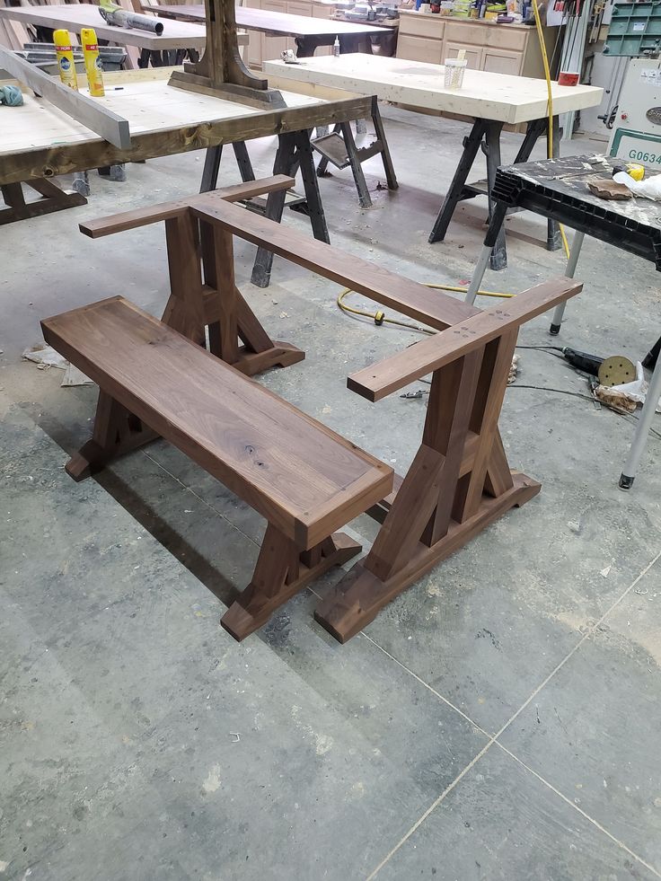 several tables and benches are being constructed in a workshop with woodworking tools on the floor