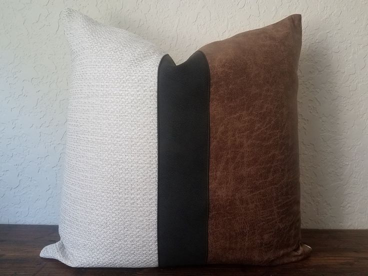 a brown and white pillow sitting on top of a wooden table next to a wall