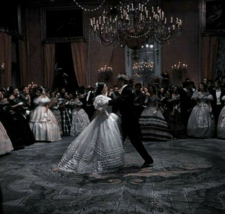 a bride and groom dance in front of a large group of people dressed in formal dress