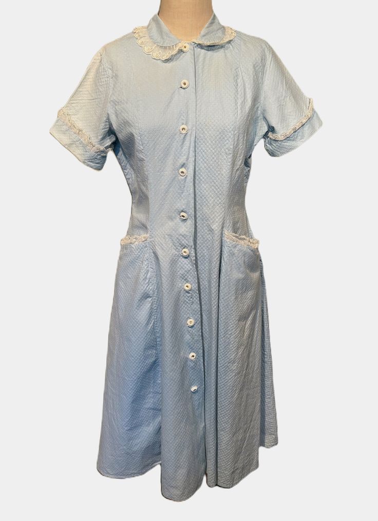 This is a cute vintage dress from the 50s.  Lable reads, Valley Frocks. Tagged a size 18. The bust measures 38", waist 34", hip 38", see measurements below.   Made of a light blue seersucker cotton. Fabric is made to be puckered. It has short sleeves with sheer, embroidered lace trim. The same trim accents the Peter Pan collar. Closes down the front with white plastic buttons that once had rhinestone centers, but they are all missing. There are large pockets on both front hips, also trimmed in the same trim. The dress nips in at the waist & has a full skirt. It is mid-calf length. The dress is in fair to good condition.  The buttons are missing the rhinestones & have glue marks where the stones were. The fabric shows patches of fading & color loss, most notable on the sleeves & sides of th Lined Knee-length Vintage Cotton Dress, 1950s Style Short Sleeve Lined Dress, 1950s Style Lined Short Sleeve Dresses, Vintage Light Blue Cotton Dress, Light Blue Vintage Cotton Dress, Vintage Light Blue Knee-length Dress, 1950s Style Lined Dresses For Daywear, Vintage Blue Dresses With Pockets, Blue Vintage Dresses With Pockets