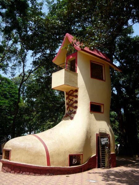 a house shaped like a shoe sitting on top of a brick road next to trees