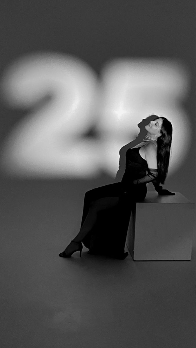 a black and white photo of a woman sitting on top of a box with her hair blowing in the wind