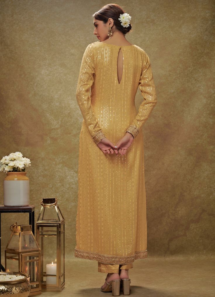 Introducing the elegant Champagne Gold Sequin Embroidered Kurta Pants Set, crafted from luxurious viscose georgette, this ensemble exudes sophistication and grace. The full-sleeved gold kurta is beautifully adorned with intricate sequin and thread embroidery, adding a touch of glamour to the look. Paired with straight-fit ankle-length pants, tailored silhouette that ensures both comfort and style. The ensemble is completed with a delicate net dupatta, featuring matching borders and scattered bootis, adding an ethereal charm. Perfect for Haldi, Mehndi, Sangeet, or as wedding guest attire, this outfit effortlessly combines traditional craftsmanship with contemporary elegance. Composition : Kurta - Viscose Georgette, Pants - Heavy Cotton Satin and Dupatta - Soft net Care: Dry Clean Only and V Reception Palazzo Set With Gold Embroidery, Anarkali Palazzo Set With Zari Work And Long Sleeves, Gold Palazzo Set With Embroidery And Straight Kurta, Gold Palazzo Set With Straight Kurta And Gold Embroidery, Festive Long Sleeve Georgette Palazzo Set, Elegant Palazzo Set With Gold Embroidery For Reception, Long Sleeve Palazzo Set With Resham Embroidery For Diwali, Diwali Long Sleeve Palazzo Set With Resham Embroidery, Festive Long Sleeve Palazzo Set With Zari Work