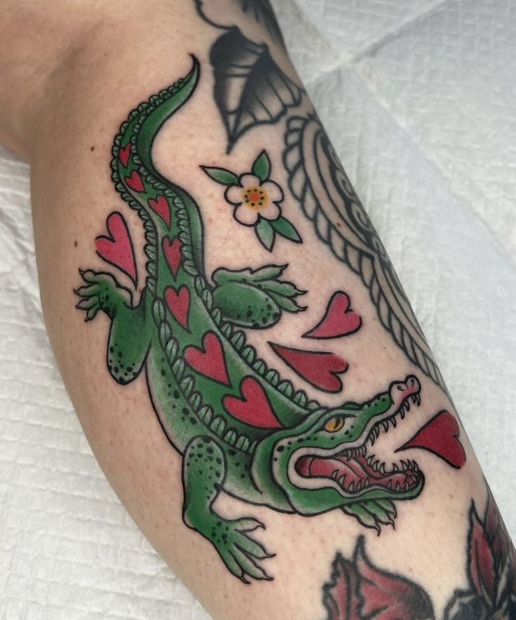 a green lizard with hearts and wings on his arm