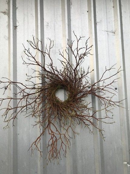 a wreath made out of branches on the side of a metal building with no leaves