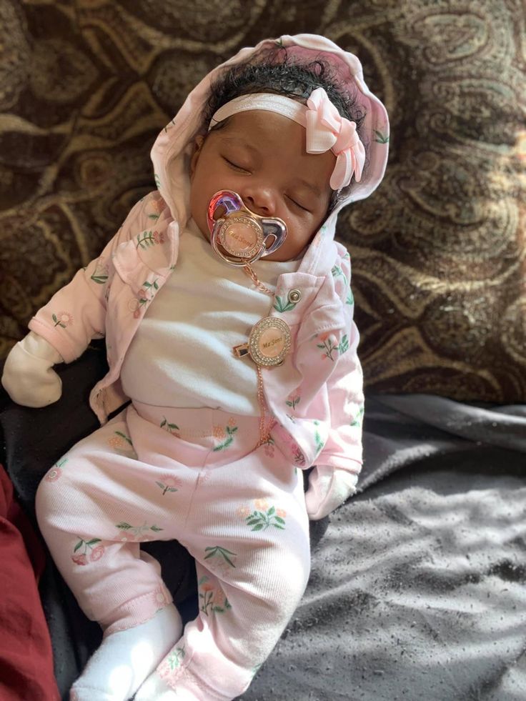 a baby is sleeping with a pacifier in it's mouth and wearing a pink outfit