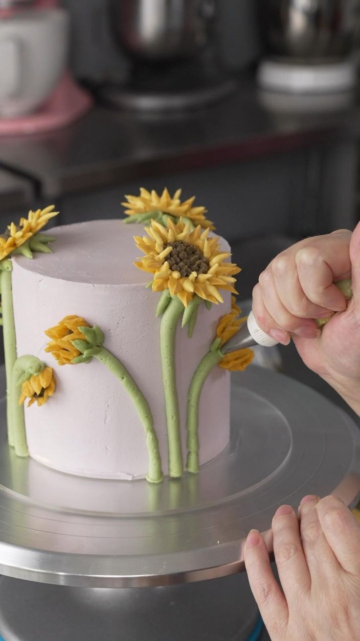 someone decorating a cake with sunflowers on it