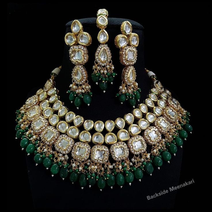 a necklace and earring set with green stones, pearls and emeralds on display