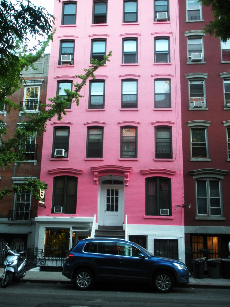 a blue car parked in front of a pink building with lots of windows on it