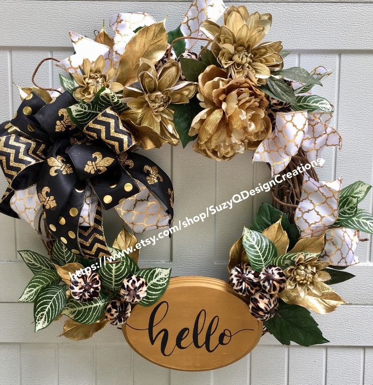 a wreath with gold and black flowers is hanging on the front door to say hello