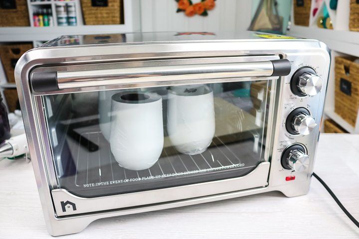 two white mugs are in the toaster oven