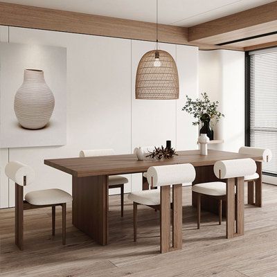 a dining room table with white chairs and a vase on the wall next to it