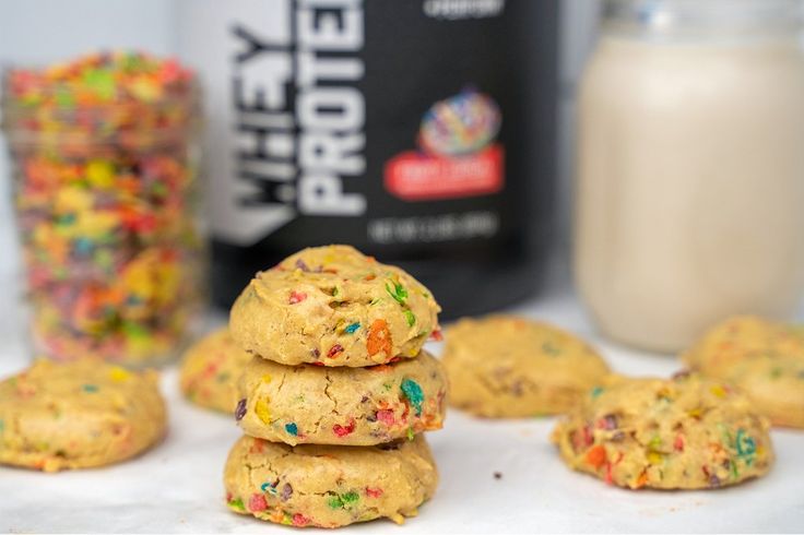 a stack of cookies with sprinkles next to a bottle of protein powder