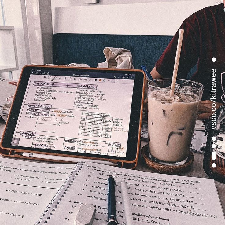 a person sitting at a table with a laptop and a drink in front of them