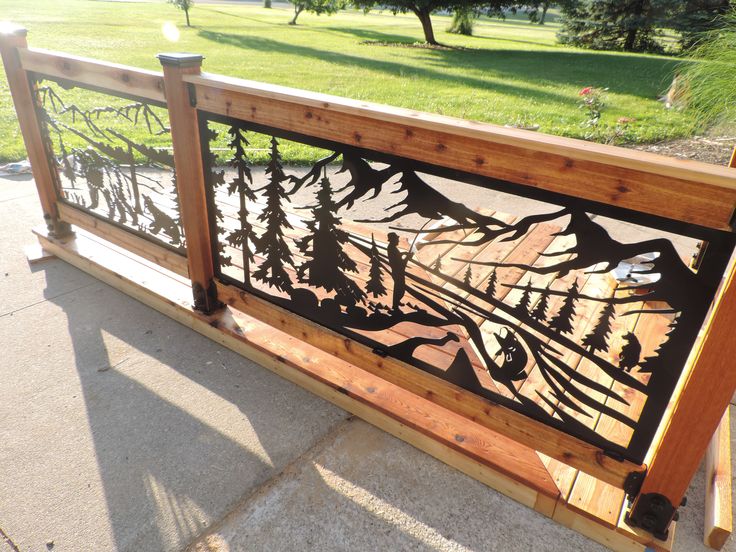 a metal fence with trees and mountains on it