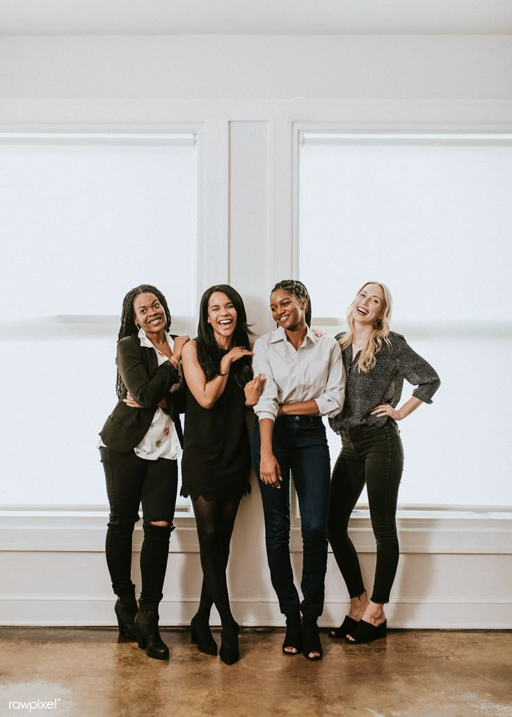 three women standing next to each other in front of two windows smiling at the camera