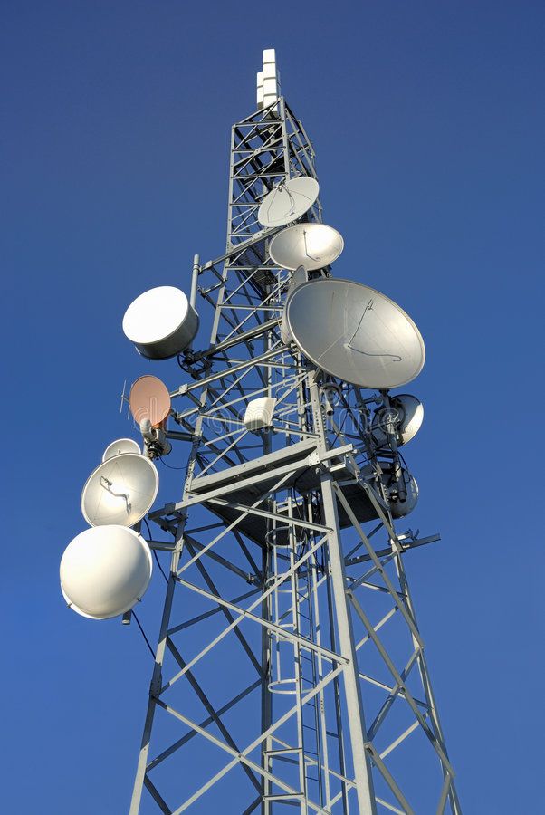 a tall tower with lots of white dishes on it's sides and blue sky in the background