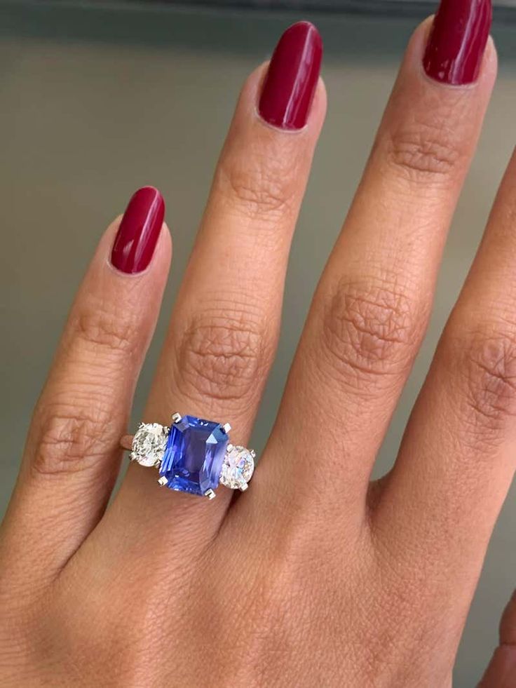 a woman's hand with a ring on it and a blue stone in the middle