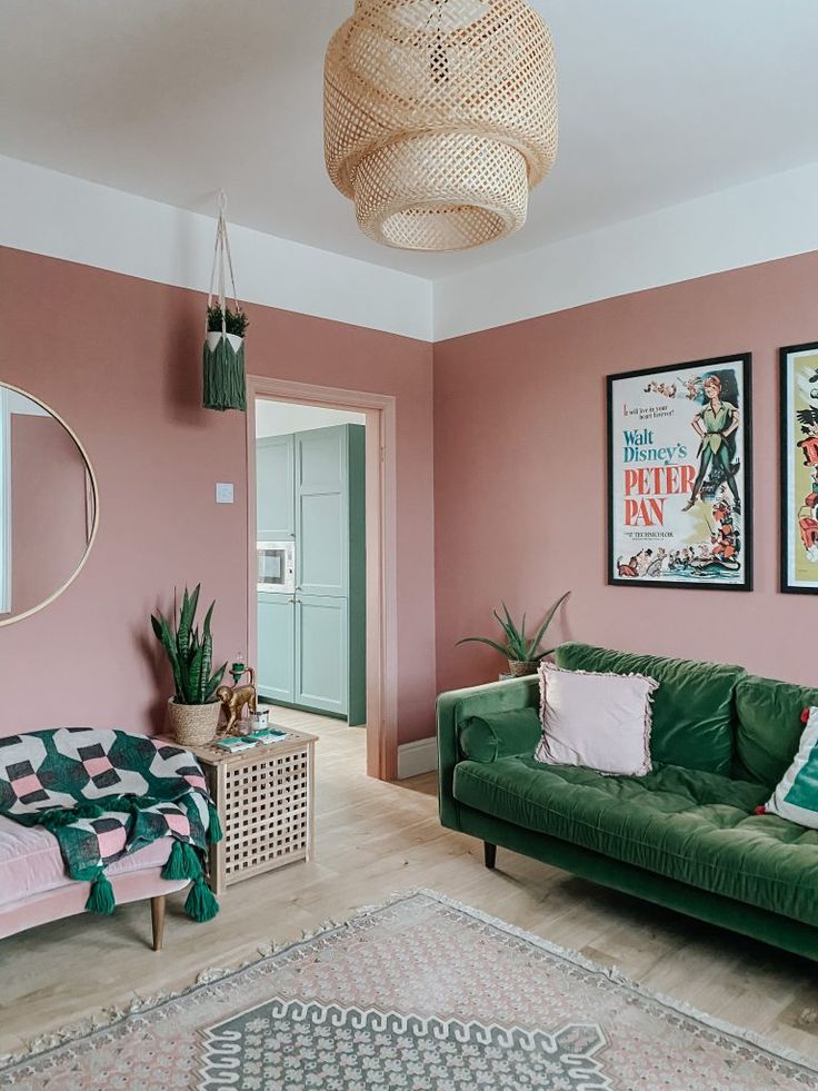 a living room with pink walls and green couches in front of two pictures on the wall