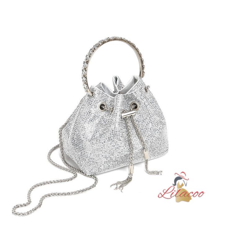 Indulge in the luxurious appeal of this sparkling silver handbag, a perfect blend of glamour and practicality. The exterior is adorned with countless tiny crystals, creating a shimmering effect that will undoubtedly capture attention at any event. The bag features a drawstring closure, adding a touch of modernity to its classic bucket bag design. The silver-tone metal handle is not only stylish but also sturdy, ensuring easy and comfortable carrying. Additionally, it comes with a detachable silv Silver Handbag, Luggage Sizes, Bag Design, Metal Chain, Chain Styles, Chain Strap, Luggage Bags, Fabric Care, Bucket Bag