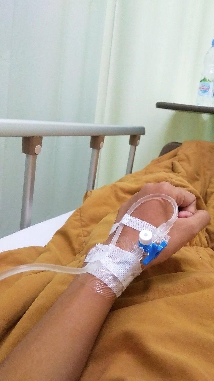 a person laying in a hospital bed with an iv tube attached to their arm and hand