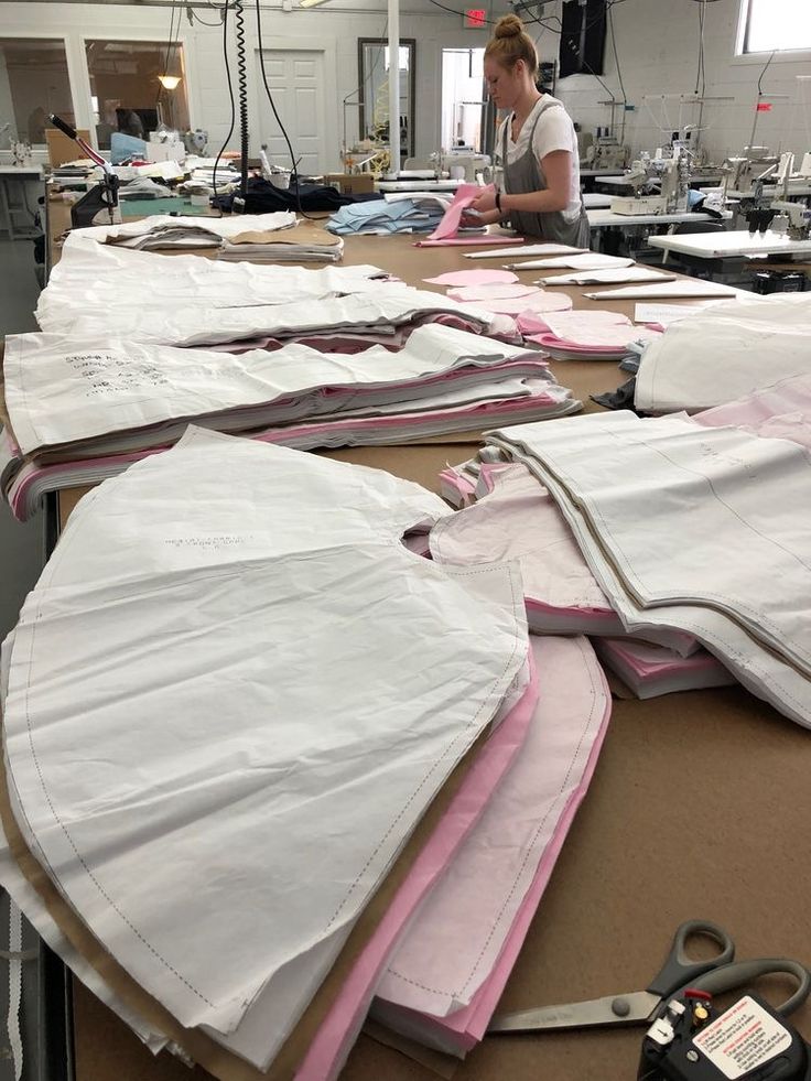 a woman working in a factory with many pieces of clothing