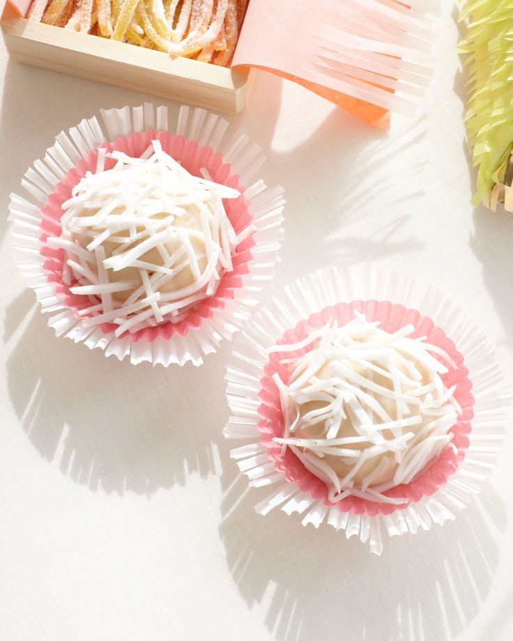 three desserts in pink and white paper on a table