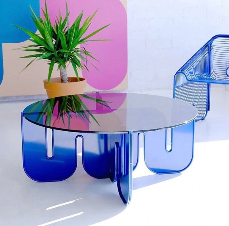 a glass table with blue legs and a potted plant on top