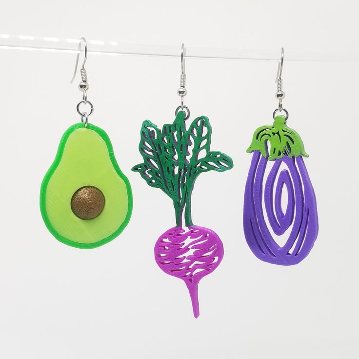 three earrings hanging from a clothes line with an avocado, radish and spinach