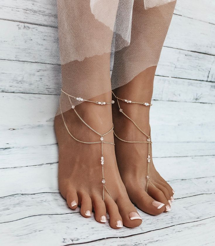 You will absolutely fall in love with Mira Barefoot Sandals in gold. This gorgeous pair of stunning foot jewelry is handcrafted using 2mm gold plated curb chain, 4mm Bicone Crystal beads, 2mm white pearls and adjustable closure on the back of the sandals. Perfect if you are getting married on the beach and want to feel the sand between your toes as you walk down the aisle.  Sold as a pair. Gift wrapped and shipped to your doorsteps within 2 business days from purchase. Expedited shipping is available when you checkout.  Mira Barefoot Sandals are available in silver, gold and rose gold. Adjustable closure on the back accommodates all foot sizes.  All rights reserved @ Bare Sandals LLC 2022. Copying photos / listings descriptions or reproducing jewelry which simulates our designs is prohibit Bohemian Gold Body Jewelry For The Beach, Bohemian Gold Barefoot Sandals, Gold Beaded Bohemian Barefoot Sandals, Elegant Handmade Barefoot Sandals For Gift, Handmade Elegant Barefoot Sandals For Gift, Delicate Gold Body Jewelry For Party, Elegant Barefoot Sandals With Ankle Strap As A Gift, Elegant Ankle Strap Barefoot Sandals As Gift, Dainty Gold Festival Body Jewelry