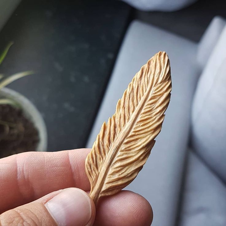 a person holding a small piece of wood with a feather on it's tip