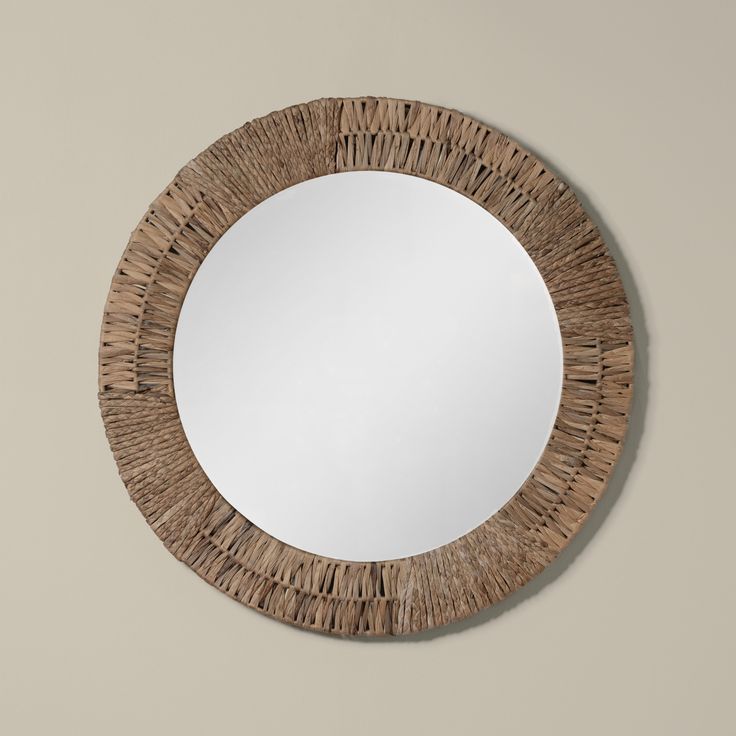 a round mirror made out of wicker with a wooden frame on the wall above it