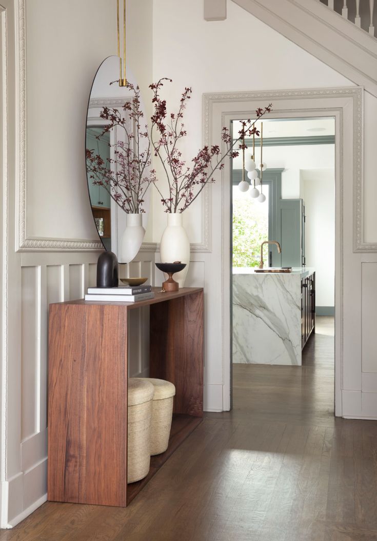 a hallway with white walls and wooden flooring next to a mirror on the wall