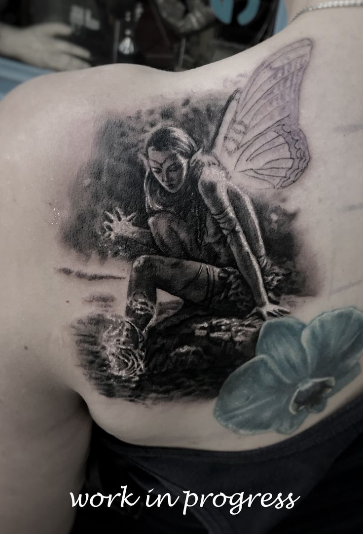 a woman's back with a tattoo on it that shows a fairy sitting on a rock