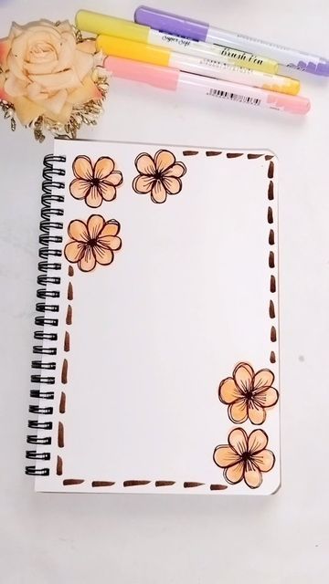 an open notebook with flowers on it next to markers