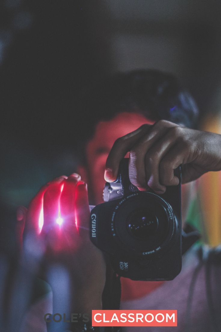 a person holding a camera up to their face with the light shining on her hand