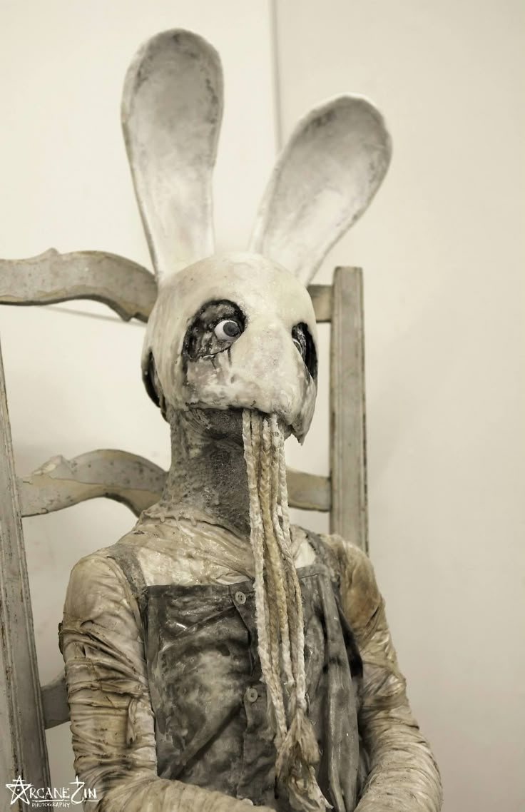 a statue of a rabbit sitting in a chair with its head turned to the side