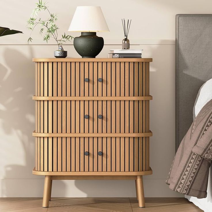 a wooden dresser next to a bed with a lamp on top of it in a bedroom