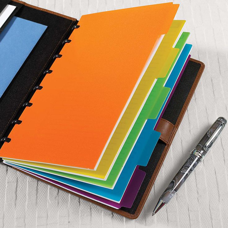 a stack of colorful notebooks with a pen next to them